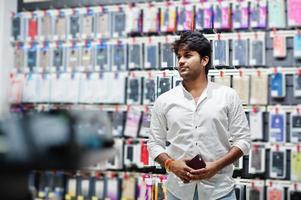 Indian man customer buyer at mobile phone store choose a case for his smartphone. South asian peoples and technologies concept. Cellphone shop. photo