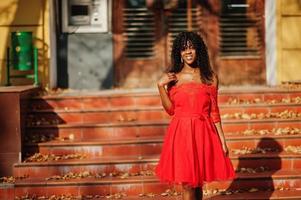 elegante mujer rizada afro francia de moda posó en el día de otoño con vestido rojo. modelo de mujer africana negra. foto