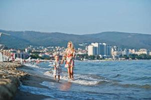 madre e hija hermosa divirtiéndose en la playa. retrato de mujer feliz con linda niña de vacaciones. foto