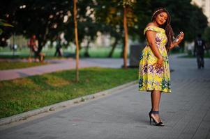 Cute small height african american girl with dreadlocks, wear at coloured yellow dress, posed at sunset. photo