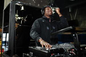 African american dj play music on decks at night club. photo