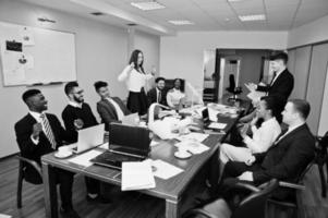 Multiracial business team meeting around boardroom table, two team leaders throw paper up. photo