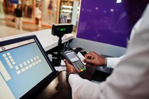 el camarero afroamericano en el bar usa una terminal de tarjeta de crédito en el cajero. foto