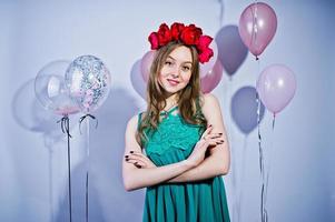 Happy girl in green turqoise dress and wreath with colored balloons isolated on white. Celebrating birthday theme. photo