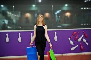 chica con bolsas de compras en el centro comercial contra la pared del club de bolos. foto