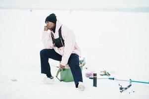 pescador afroamericano en el mar congelado. pesca de invierno. foto