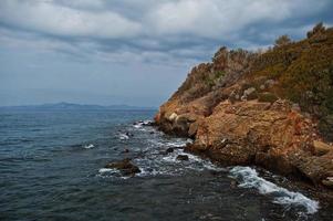 la ola del mar se rompe en el paisaje de rocas de la playa. las olas del mar chocan y salpican rocas en bodrum, turquía. foto