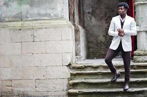 pensativo joven apuesto caballero afroamericano en ropa formal. hombre modelo elegante negro con chaqueta blanca. foto