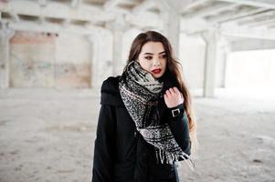 chica casual con estilo morena en bufanda contra el lugar de la fábrica abandonada. foto