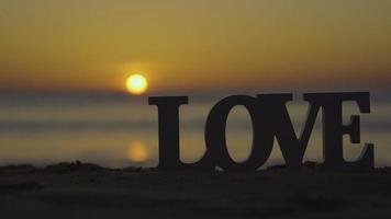 Letter Love on the beach sand sunset background. video