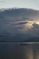 pescador en su barco al atardecer. barco de pescadores al atardecer foto