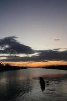 pescador en su barco al atardecer. barco de pescadores al atardecer foto