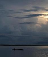 pescador en su barco al atardecer. barco de pescadores al atardecer foto