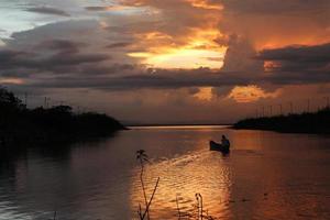 pescador en su barco al atardecer. barco de pescadores al atardecer foto