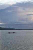 pescador en su barco al atardecer. barco de pescadores al atardecer foto