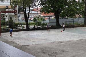 gorontalo-indonesia, junio de 2022 - niños practicando fútbol en una cancha de baloncesto durante el día foto