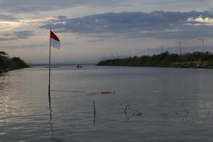 Indonesian flag fluttering against the background of the lake and the sky in the afternoon photo