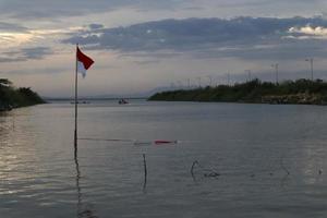 Indonesian flag fluttering against the background of the lake and the sky in the afternoon photo