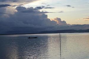 pescador en su barco al atardecer. barco de pescadores al atardecer foto