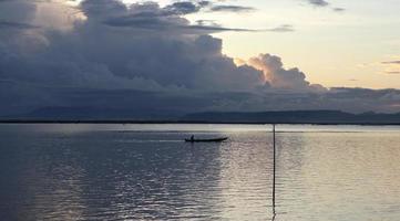 pescador en su barco al atardecer. barco de pescadores al atardecer foto