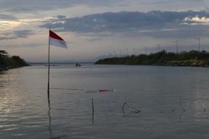 Indonesian flag fluttering against the background of the lake and the sky in the afternoon photo