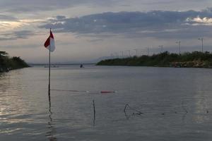 Indonesian flag fluttering against the background of the lake and the sky in the afternoon photo