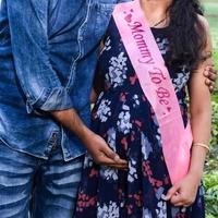 pareja india posando para una sesión de fotos de maternidad. la pareja está posando en un césped con hierba verde y la mujer está faluntando su panza en el jardín lodhi en nueva delhi, india