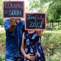 Indian couple posing for maternity baby shoot. The couple is posing in a lawn with green grass and the woman is falunting her baby bump in Lodhi Garden in New Delhi, India photo