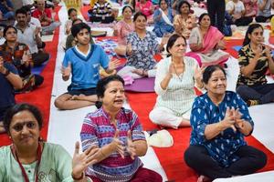 nueva delhi, india, 19 de junio de 2022 - sesión grupal de ejercicios de yoga para personas de diferentes edades en el templo balaji, vivek vihar, día internacional del yoga, gran grupo de adultos que asisten a clases de yoga en el templo foto