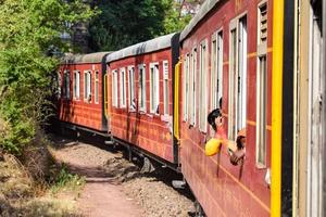 Toy Train moving on mountain slopes, beautiful view, one side mountain, one side valley moving on railway to the hill, among green natural forest. Toy train from Kalka to Shimla in India, Indian Train photo