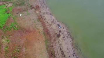 vecchia barca di legno sulla riva del fiume tra i ramoscelli rifiuti con fiumi calmi. video