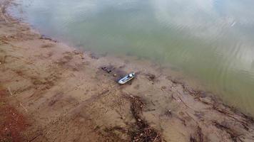 viejo barco de madera en la orilla del río entre los desechos de ramitas con ríos tranquilos. video