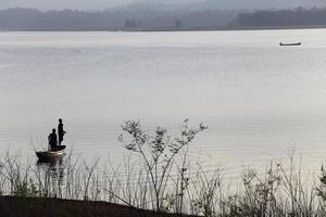 silueta de pescador en bote de madera en el lago. foto