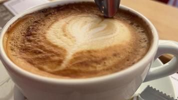 Cup of cappuccino with foam in the shape of heart stirred with a spoon video