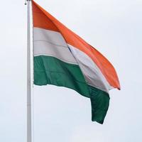 India flag flying high at Connaught Place with pride in blue sky, India flag fluttering, Indian Flag on Independence Day and Republic Day of India, tilt up shot, Waving Indian flag, Har Ghar Tiranga photo