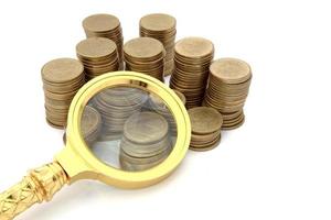 Magnifier and gold coins. On a white background. photo