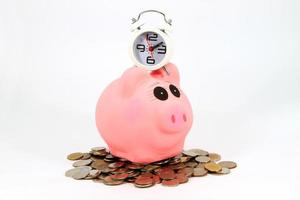 A piggy bank with coins and an old fashioned clock on a white background. photo