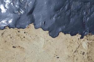 crude oil spill on the stone at the beach photo