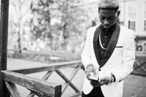 Chic handsome african american man in white suit with mobile phone at hand. photo