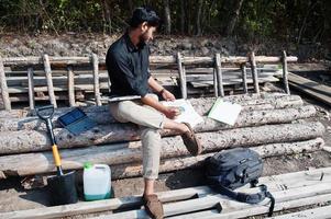 South asian agronomist farmer looking at diagram papers on farm. Agriculture production concept. photo