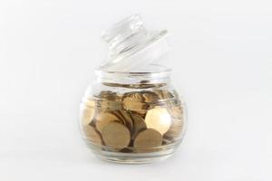 Glass bank for tips with money isolated on white photo
