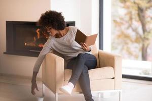 mujer negra leyendo un libro frente a la chimenea foto