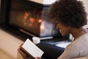 mujer negra leyendo un libro frente a la chimenea foto