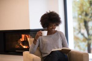 mujer negra leyendo un libro frente a la chimenea foto