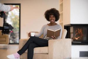 black woman reading book  in front of fireplace photo