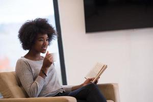 black woman reading book  in front of fireplace photo