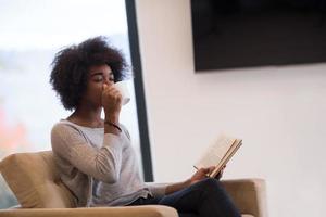 black woman reading book  in front of fireplace photo