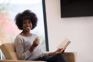 black woman reading book  in front of fireplace photo