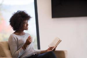 mujer negra leyendo un libro frente a la chimenea foto