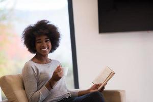 mujer negra leyendo un libro frente a la chimenea foto